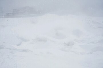 A blizzard covering a mountain pass, with snowdrifts burying the road and limiting visibility.