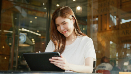 woman using tablet in cafe, smiling and enjoying her time. businesswoman remote work digital nomad