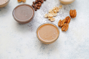 Homemade nuts butter in a glass jars with various nuts.