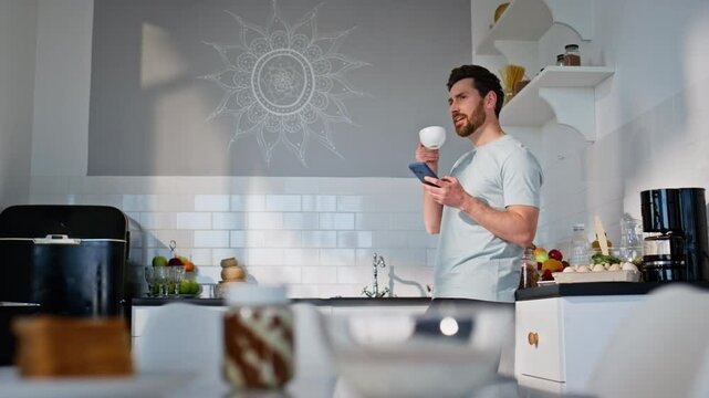 Morning man using mobile phone drinking espresso apartment. Guy reading emails