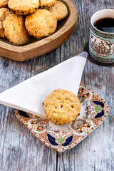 A small plate with a home baked biscuit next to a dish of biscuits and a cup of tea