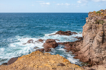 Coastline of Sant'Antioco Island with high red cliffs and rough sea