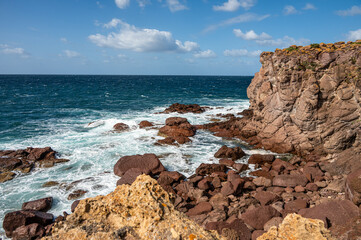 Coastline of Sant'Antioco Island with high red cliffs and rough sea