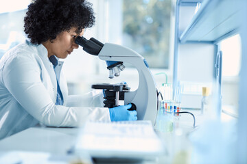 Multiracial  female scientist working on a research through a microscope in laboratory.