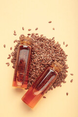 Flaxseeds with flaxseed oil in glass bottle on beige background.