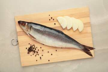 Fresh herring fish on cutting board on grey background