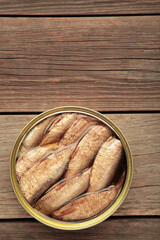 Opened can with sprats in oil on grey wooden background