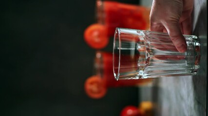Process of preparing cocktail. Hand pouring glass with beverage. Garnishing with salt, tomato and straw. Drink aesthetics.