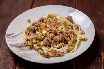 Udon with minced meat and vegetables in sauce in a plate on the table