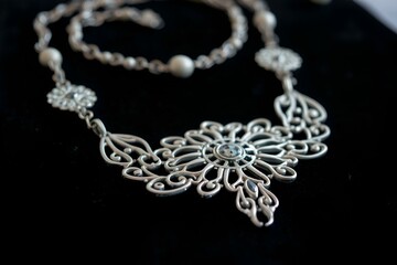 Elegant silver necklace with intricate floral design displayed on a dark background

