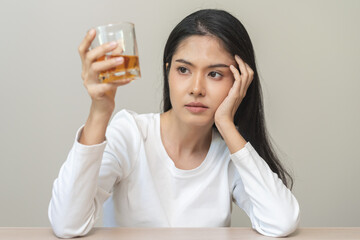 Alcoholism drunk, sad asian young woman hand holding glass of alcohol or whiskey, alone depressed female drink booze on background. Treatment of alcohol addiction, suffer abuse problem alcoholism.