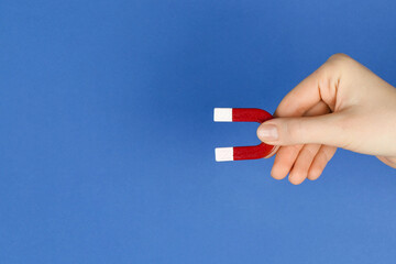 Woman with horseshoe magnet on blue background, closeup. Space for text