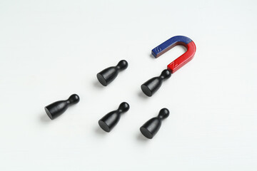 Magnet attracting black game pieces on white background