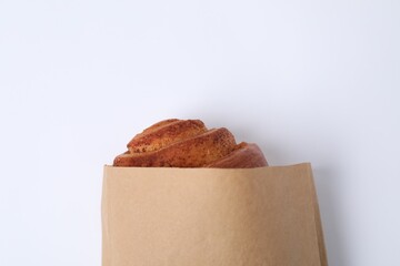 Paper bag with freshly baked bun on white background, top view