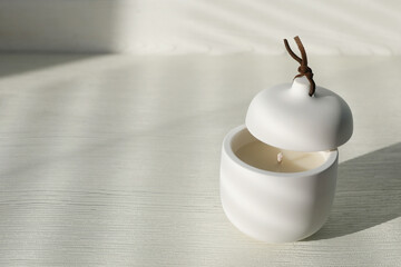 Soy candle and lid on white wooden table, space for text