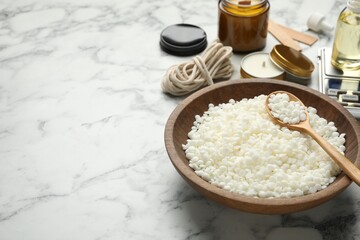 Soy wax and other supplies for making candles on white marble table, closeup. Space for text
