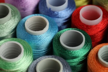 Different spools of sewing threads as background, closeup
