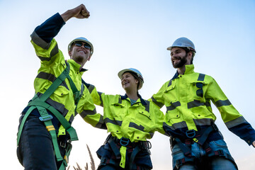 Group of professional males and female wind turbine engineers cheering up feeling happy working in...