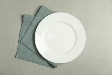 Napkin and empty plate on grey table, top view
