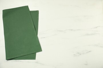 Green napkin on white marble table, top view. Space for text