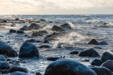 landscape with the seashore, windy winter day, water splashes, icy stones on the seashore, Baltic...