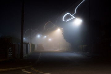 An eerie foggy suburban road at night. With blurred light trails.