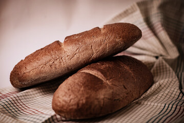 Two freshly baked loaves of bread placed on a checkered cloth. Warm tones and natural lighting emphasize the rustic and homemade feel, perfect for bakery, food, or rustic lifestyle themes.