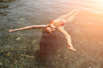 Fototapeta premium Happy woman sea relaxing floating in transparent sea water on summer holiday. Travel leisure recreation lifestyle, female in nature.