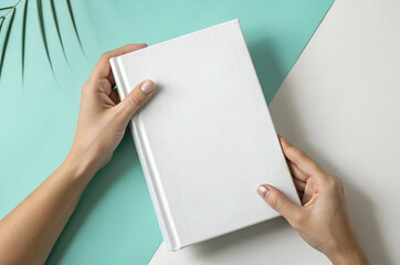 Obraz premium White Book Cover Mockup: Hands Holding a Textured Book Against a Pastel Background