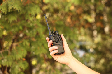 Woman with walkie talkie in park, closeup