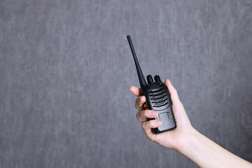 Woman with walkie talkie against grey background, closeup. Space for text