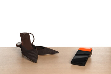 Payment terminal and shoes on wooden table against white background