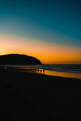 silueta de personas andando por la playa al atardecer 