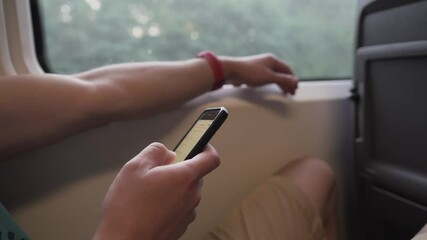 Man using mobile phone on a high speed train. Male on mask face protection, use smartphone and keep social distancing while commuting in public transport. Travelling by train with coronavirus. - Powered by Adobe