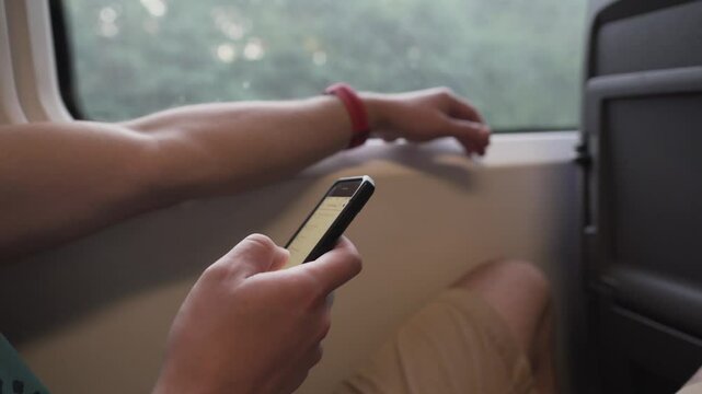 Man using mobile phone on a high speed train. Male on mask face protection, use smartphone and keep social distancing while commuting in public transport. Travelling by train with coronavirus.
