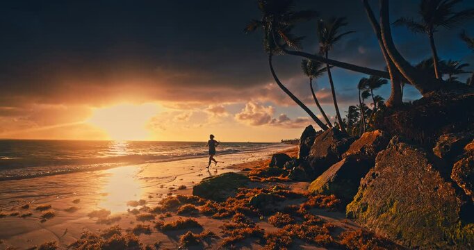 Woman jogging on sunrise on a shore of Tropical Island Beach with Palms and Ocean Waves Dominican Republic