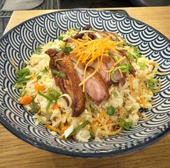 Delicious asian fried rice with grilled pork and vegetables in decorative bowl