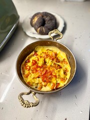 Scrambled eggs with red bell pepper in copper bowl