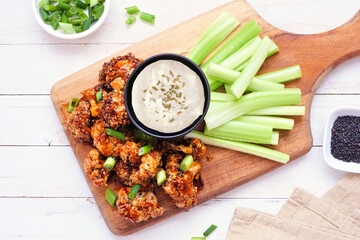 Healthy plant based honey garlic cauliflower wings with celery and ranch dip. Overhead view table...