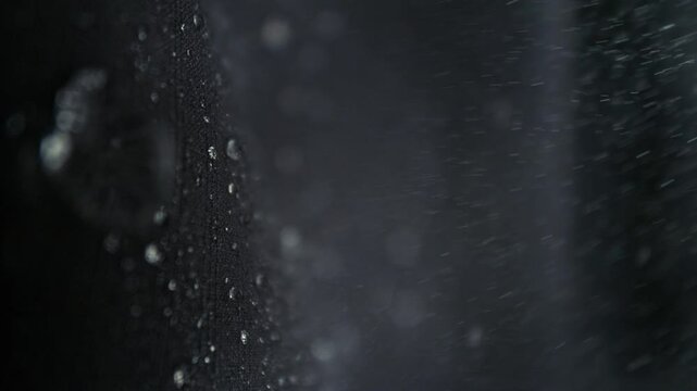 Super Slow Motion Detail Shot of Water Flow Down on Waterproof Black Cloth at 1000fps.