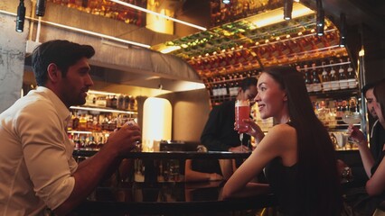 Couple making a toast with cocktail paloma and old fashioned at luxurious bar in lively conversation drinks celebrating a special party at vibrant nightclub while friend drinking Margarita. Vinosity.