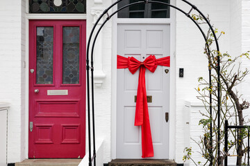 White door with big red bow and red door next to it