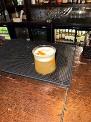 Whiskey sour cocktail at pub bar with orange peel