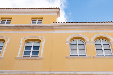 Brightly colored building facade under a clear blue sky with historical architectural features in a vibrant urban setting