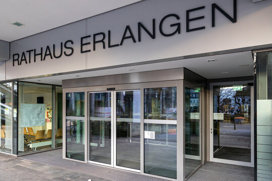 Eingang des Rathauses Erlangen. Der Schriftzug "Rathaus Erlangen" ist prominent an der Wand &uuml;ber dem Eingangsbereich angebracht.