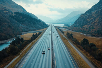 Obraz premium A scenic highway cutting through a mountainous valley, surrounded by rugged landscapes.