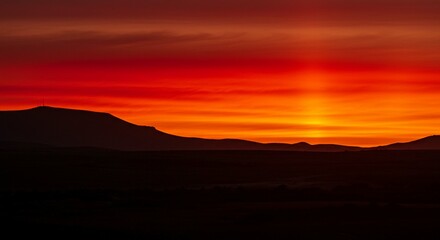Obraz premium Fiery Sunset Landscape Dramatic Silhouette of Mountains Against Vibrant Red Sky