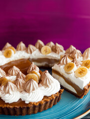 Indulgent banoffee pie slice on a blue plate with creamy layers and banana garnishes