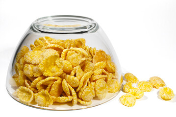 handful of cornflakes with an overturned glass plate on a white background