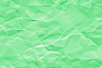 Creased or crumpled green colored paper background. Wrinkled blank sheet texture with grain or noise	
